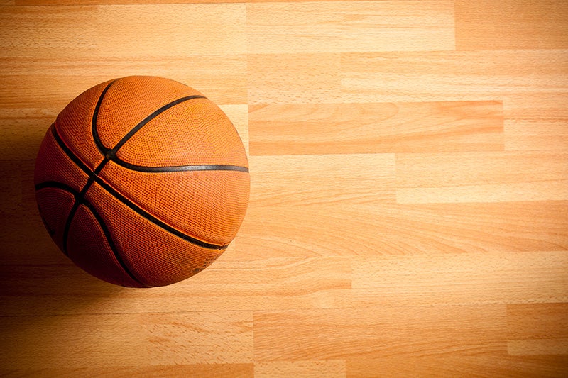 An official orange ball on a hardwood basketball court