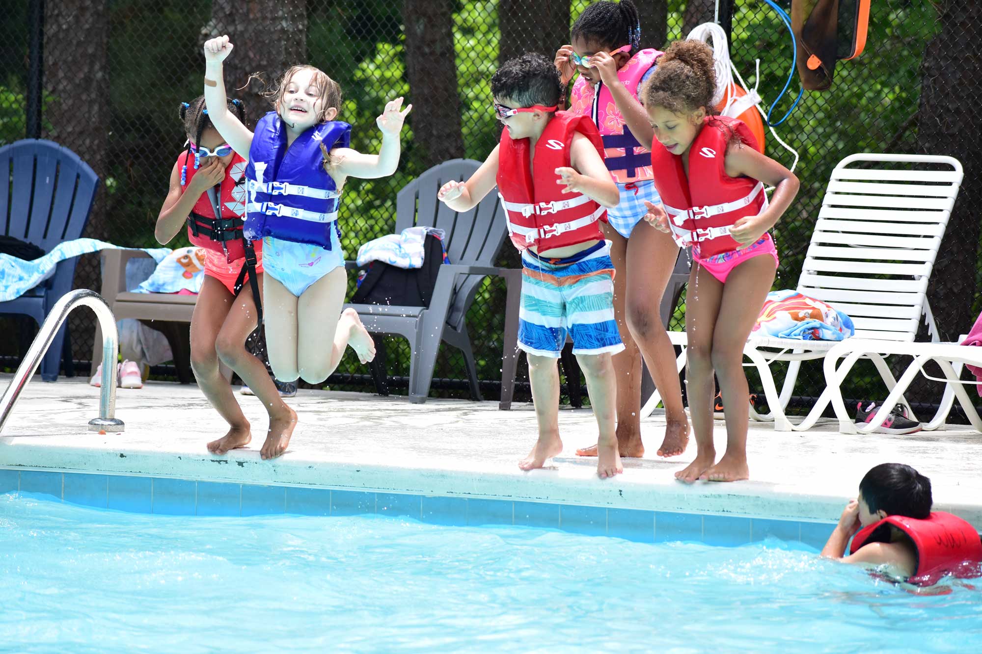 Yond kids jumping in the pool together.