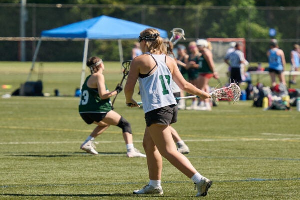 Young females playing lacrosse.