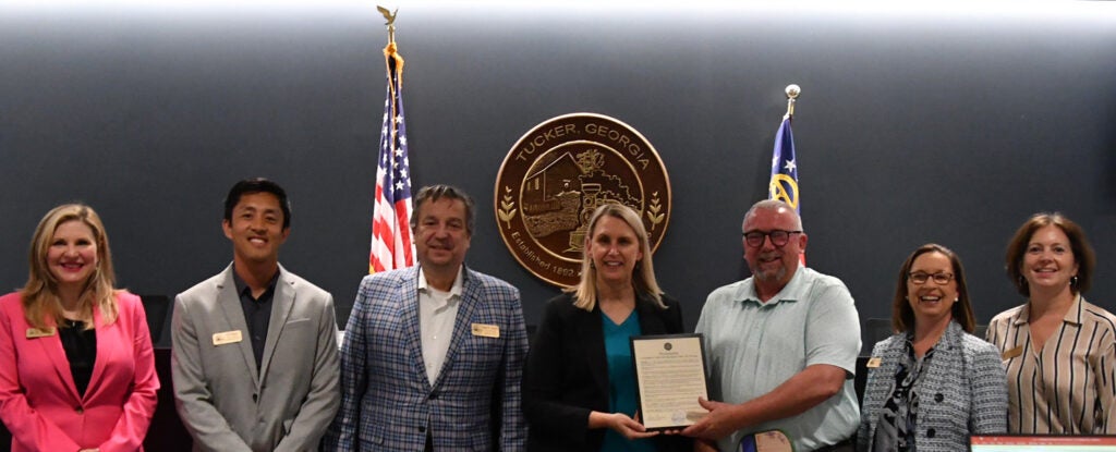 Retiring Parks & Recreation Director Rip Robertson poses with the Mayor, Council and a proclamation recognizing his work.
