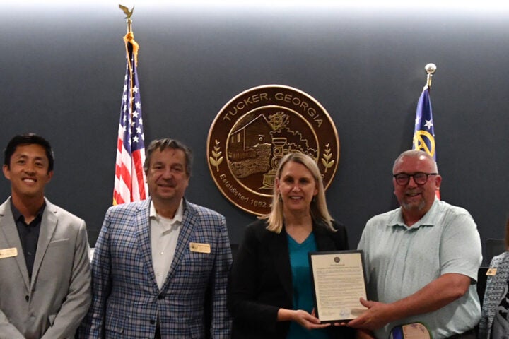 Retiring Parks & Recreation Director Rip Robertson poses with the Mayor, Council and a proclamation recognizing his work.